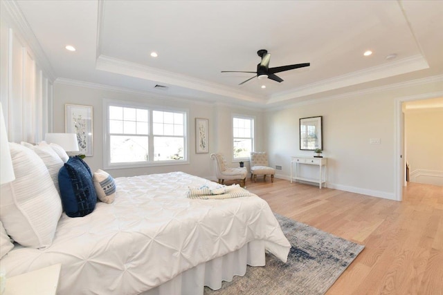 bedroom with ornamental molding, light hardwood / wood-style floors, and a raised ceiling