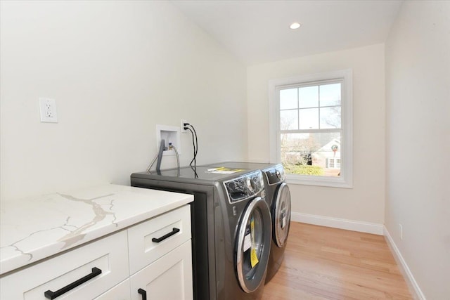 laundry room featuring cabinets, washing machine and clothes dryer, and light wood-type flooring