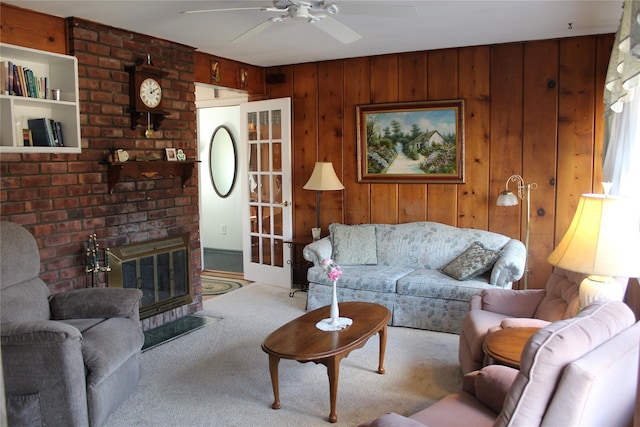 living room with light carpet, a fireplace, wooden walls, and ceiling fan