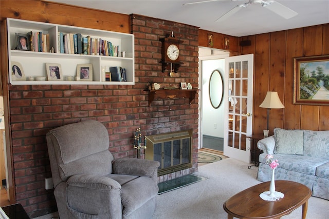 living room with a fireplace, wood walls, ceiling fan, and carpet