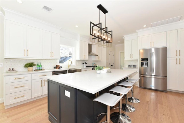 kitchen with white cabinetry, wall chimney range hood, and stainless steel appliances