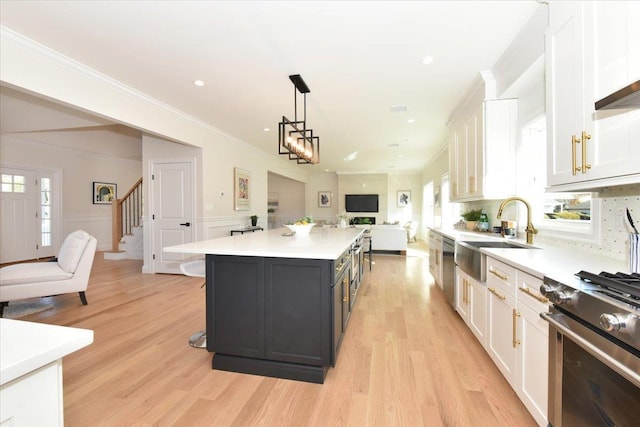 kitchen featuring sink, white cabinetry, a center island, hanging light fixtures, and light hardwood / wood-style flooring