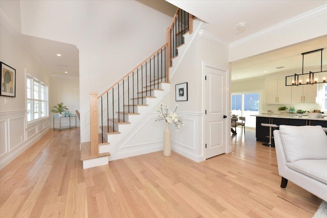 stairway featuring crown molding, a healthy amount of sunlight, and hardwood / wood-style floors