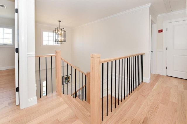 stairway with crown molding, a healthy amount of sunlight, and wood-type flooring