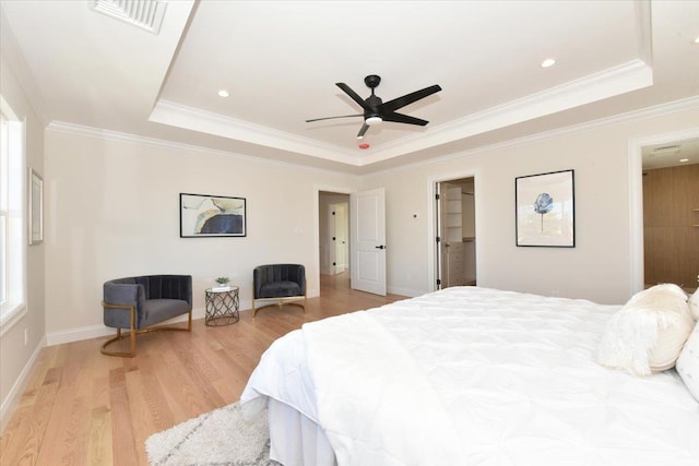 bedroom with ceiling fan, ornamental molding, a tray ceiling, and light hardwood / wood-style floors