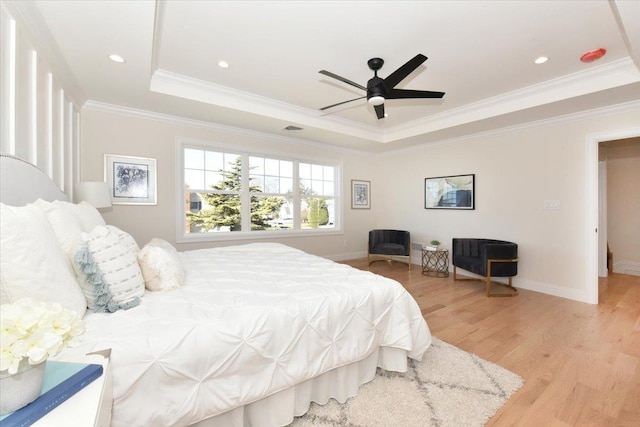 bedroom with ceiling fan, ornamental molding, a tray ceiling, and light hardwood / wood-style flooring