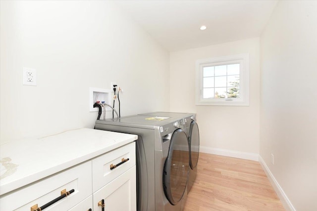 laundry room featuring washer and dryer, cabinets, and light wood-type flooring