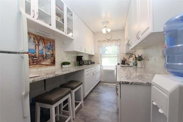 kitchen with white refrigerator, light stone countertops, decorative backsplash, and white cabinets