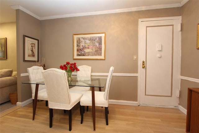 dining area with ornamental molding and light hardwood / wood-style floors