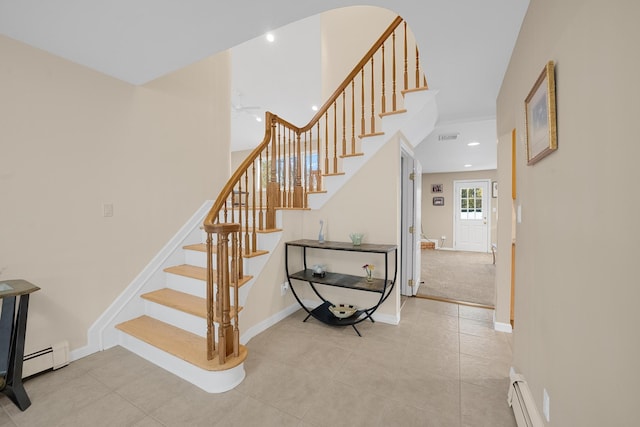 stairway featuring a baseboard heating unit and tile patterned floors