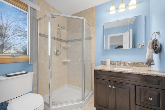 bathroom with a shower with door, vanity, tile patterned flooring, and toilet