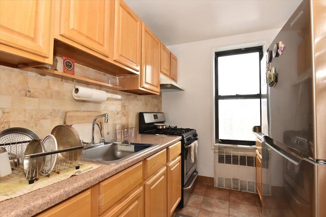 kitchen featuring radiator heating unit, a sink, stainless steel appliances, under cabinet range hood, and backsplash