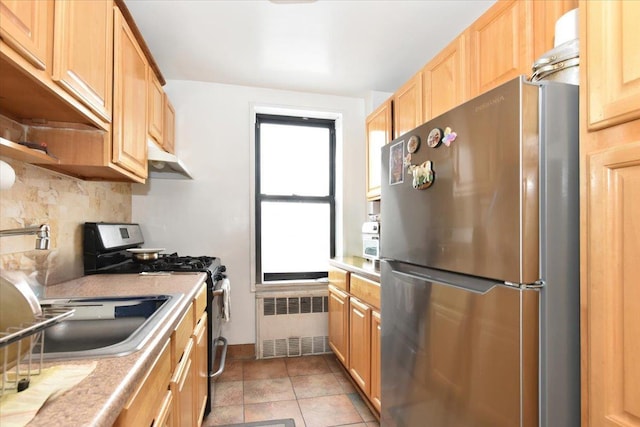 kitchen with radiator heating unit, appliances with stainless steel finishes, tasteful backsplash, and light countertops