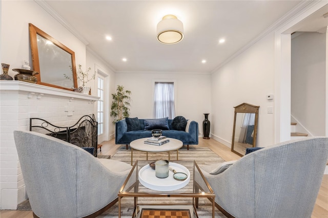 living room with ornamental molding, a brick fireplace, and light hardwood / wood-style flooring