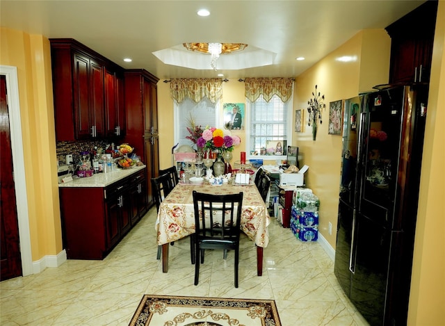 kitchen featuring a raised ceiling, black fridge, and decorative backsplash