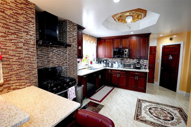 kitchen with wall chimney exhaust hood, sink, tasteful backsplash, a tray ceiling, and black gas stove