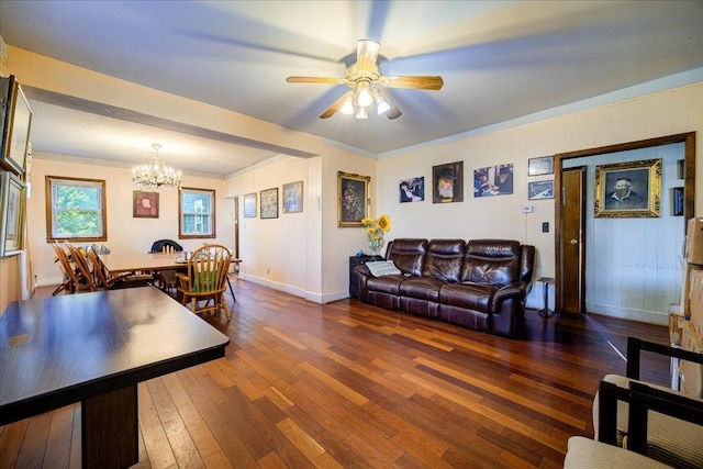 living room with ornamental molding, dark wood-type flooring, and ceiling fan with notable chandelier