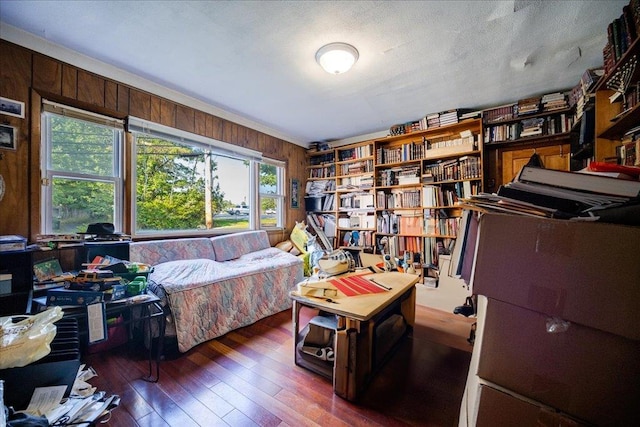 bedroom with dark hardwood / wood-style floors, a textured ceiling, and wood walls