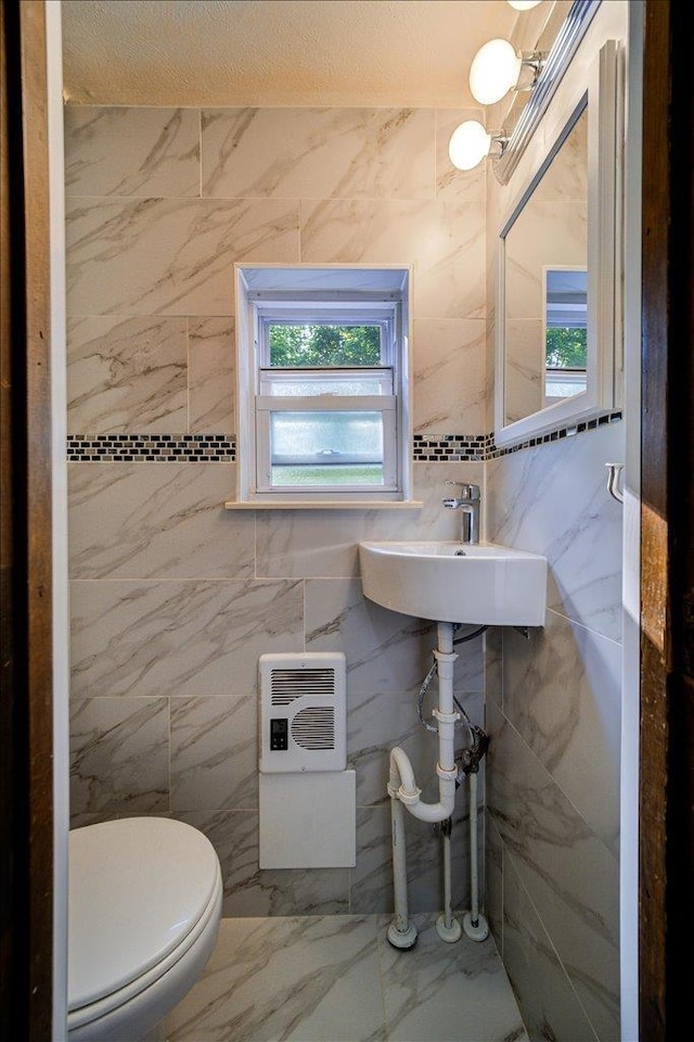 bathroom featuring sink, tile walls, and toilet