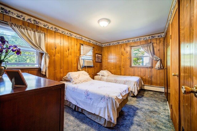 carpeted bedroom with cooling unit, a baseboard radiator, and wooden walls