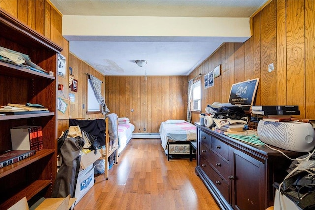 bedroom with a baseboard radiator, wooden walls, beamed ceiling, and light wood-type flooring