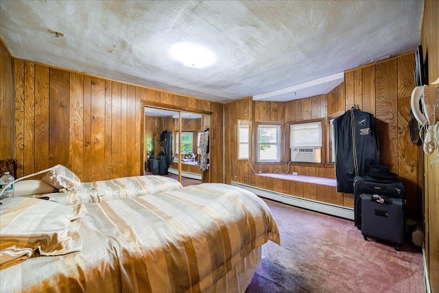 carpeted bedroom with baseboard heating, wooden walls, a closet, and cooling unit