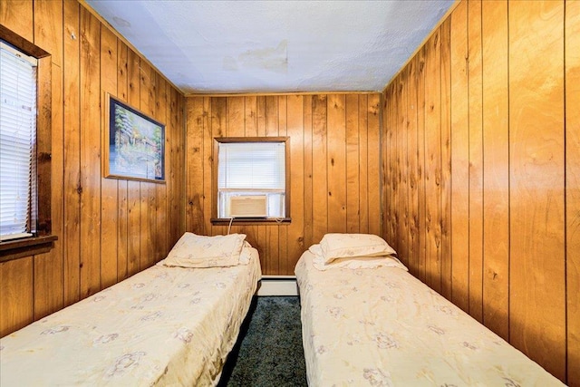 bedroom with baseboard heating, cooling unit, dark carpet, and wood walls