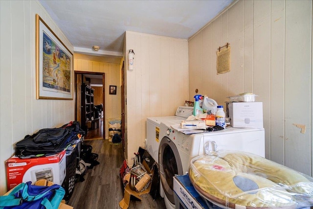 clothes washing area with dark wood-type flooring, wooden walls, and separate washer and dryer