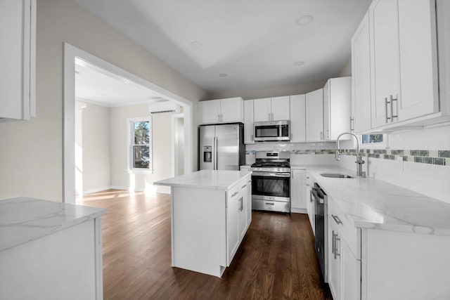 kitchen featuring sink, stainless steel appliances, white cabinets, a kitchen island, and an AC wall unit