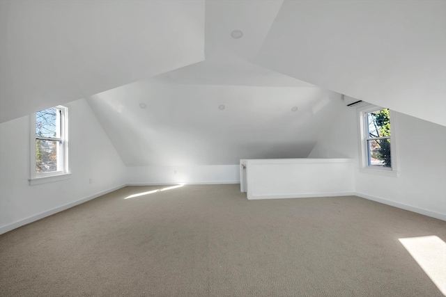 additional living space featuring plenty of natural light, light colored carpet, and lofted ceiling