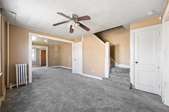 carpeted empty room featuring radiator and ceiling fan