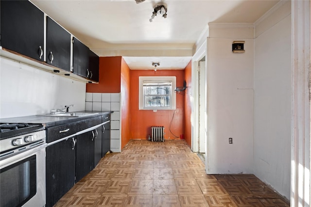 kitchen featuring sink, gas range, ornamental molding, radiator heating unit, and light parquet floors