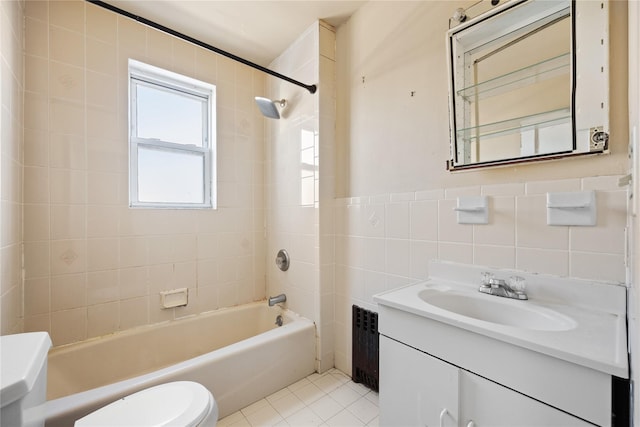 full bathroom featuring tiled shower / bath, tile walls, vanity, toilet, and tile patterned floors