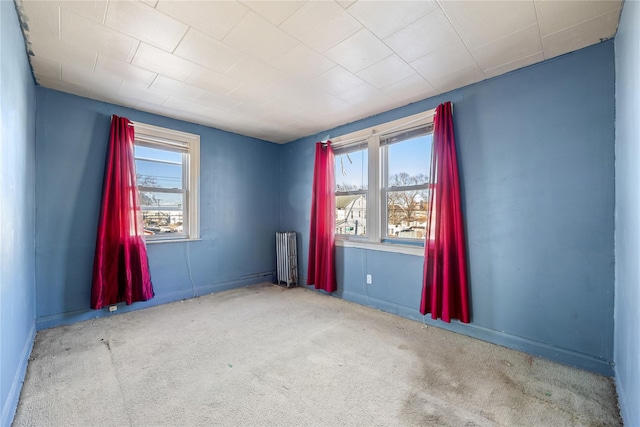 unfurnished room with radiator and light colored carpet