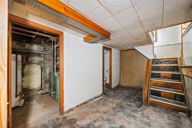 basement featuring wooden walls and gas water heater