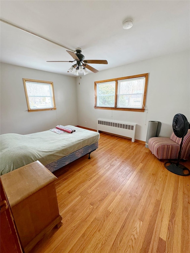 bedroom with light hardwood / wood-style flooring, radiator heating unit, and ceiling fan