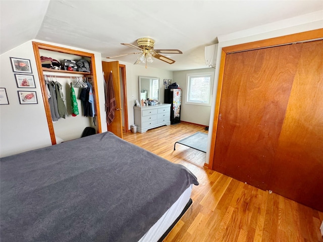 bedroom featuring ceiling fan, lofted ceiling, a wall mounted AC, and light wood-type flooring