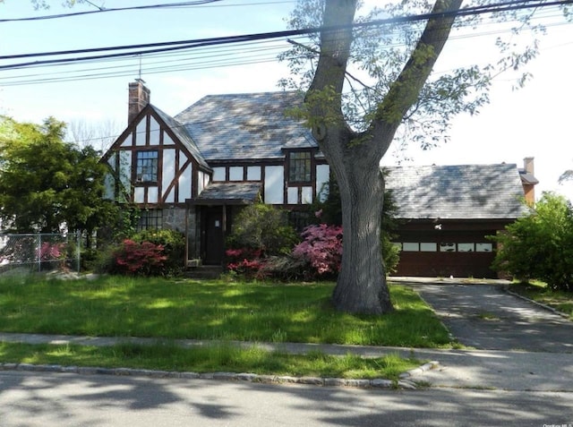 tudor home featuring a garage and a front yard