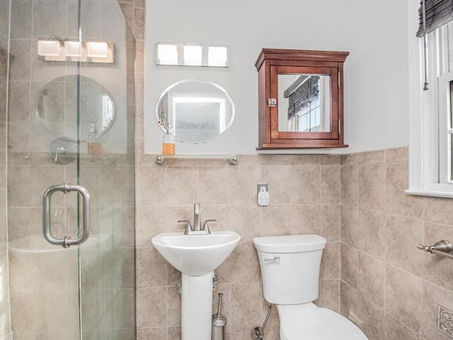 bathroom featuring a shower with door, tile walls, and toilet