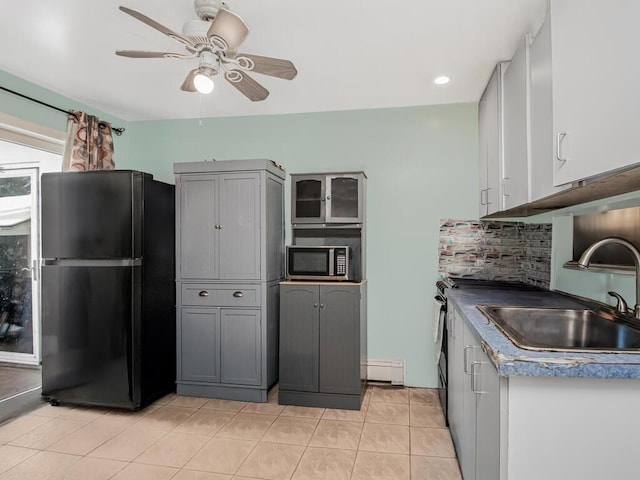 kitchen with light tile patterned flooring, sink, gray cabinetry, backsplash, and black fridge