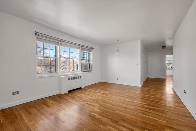 spare room featuring cooling unit, radiator, wood-type flooring, and plenty of natural light