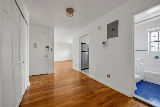 corridor with electric panel and hardwood / wood-style floors