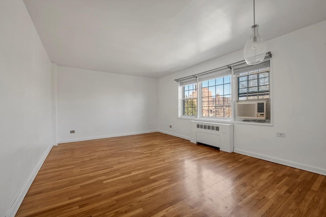 unfurnished room with cooling unit, radiator, and hardwood / wood-style floors