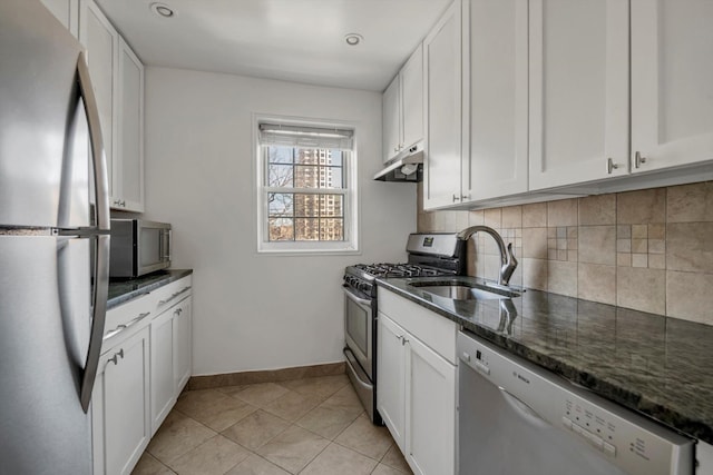 kitchen featuring appliances with stainless steel finishes, sink, dark stone counters, and white cabinets