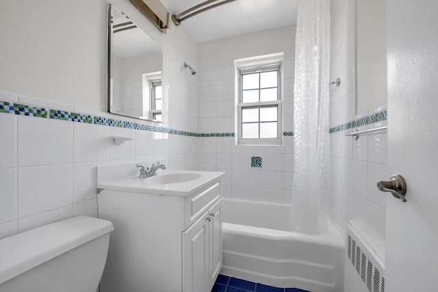 full bathroom with radiator heating unit, shower / tub combo with curtain, tile walls, vanity, and toilet