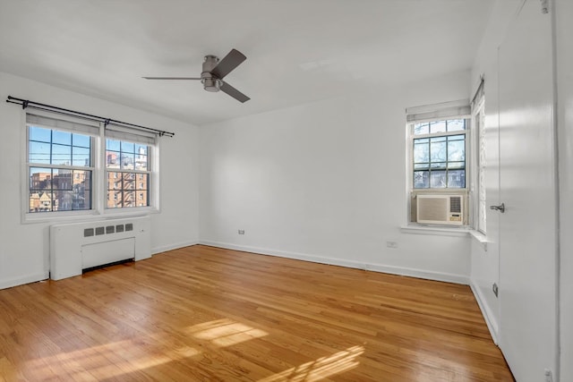 spare room featuring light hardwood / wood-style flooring, radiator heating unit, a wealth of natural light, and ceiling fan