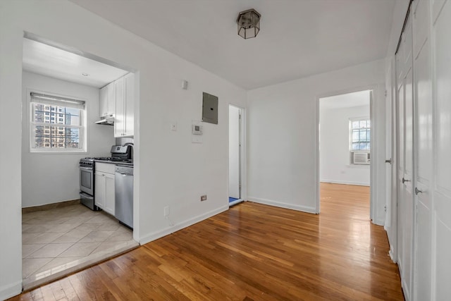 kitchen with light hardwood / wood-style flooring, appliances with stainless steel finishes, electric panel, cooling unit, and white cabinets