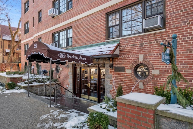 snow covered property entrance featuring cooling unit and french doors