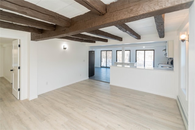 empty room featuring light wood-type flooring, beam ceiling, sink, and a baseboard heating unit