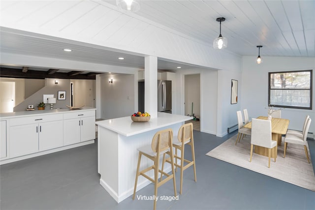 kitchen featuring lofted ceiling, baseboard heating, stainless steel fridge, pendant lighting, and white cabinets